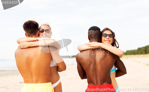 Image of happy friends or couples hugging on summer beach