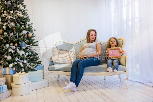 Image of Beautiful pregnant woman sitting with doughter