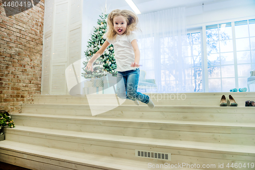 Image of Cute girl in in casual clothes jumping from staircase