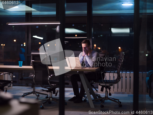 Image of man working on laptop in dark office