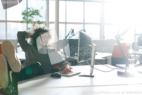 Image of businessman sitting with legs on desk