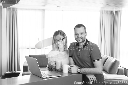 Image of couple drinking coffee and using laptop at home