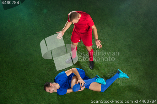 Image of Male soccer player suffering from leg injury on football green field
