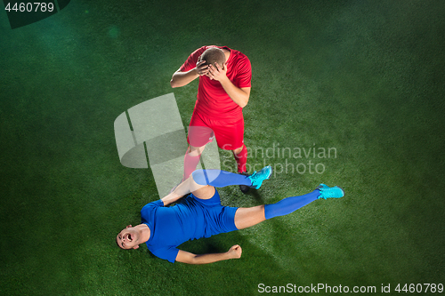 Image of Male soccer player suffering from leg injury on football green field