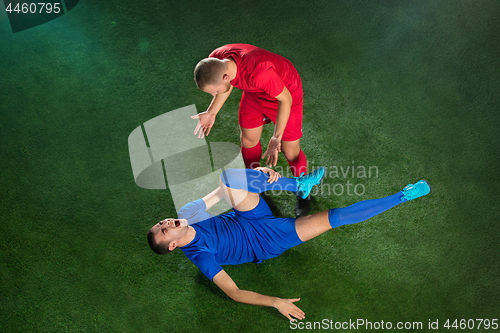 Image of Male soccer player suffering from leg injury on football green field