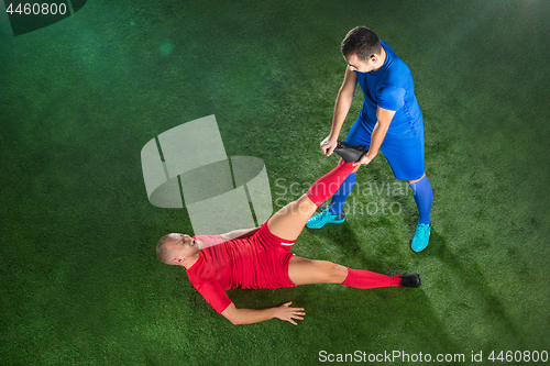 Image of Male soccer player suffering from leg injury on football green field