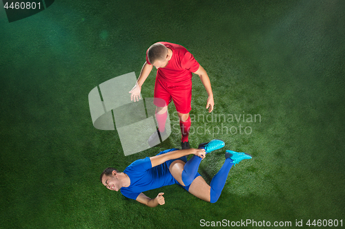 Image of Male soccer player suffering from leg injury on football green field