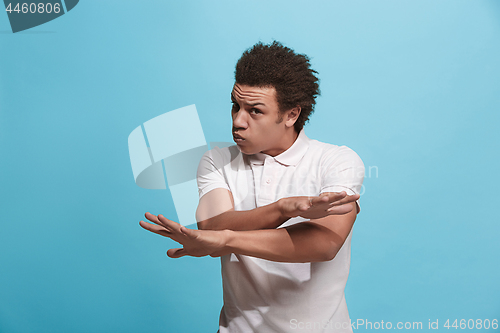 Image of Beautiful male half-length portrait isolated on blue studio backgroud. The young emotional afro man