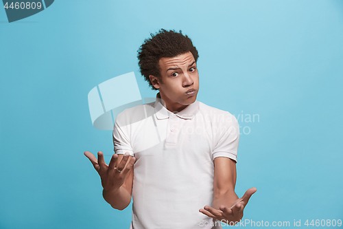 Image of Beautiful male half-length portrait isolated on blue studio backgroud. The young emotional afro man