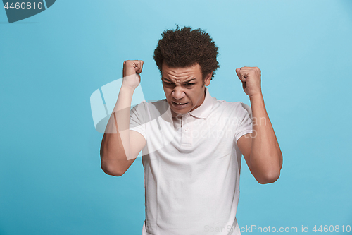 Image of The young emotional angry man screaming on blue studio background