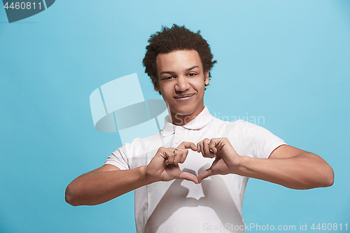 Image of The happy business man standing and smiling against blue background.