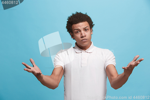 Image of Beautiful male half-length portrait isolated on blue studio backgroud. The young emotional afro man