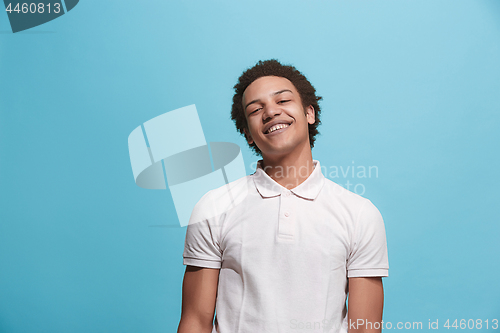 Image of The happy business man standing and smiling against blue background.