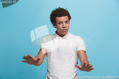 Image of Beautiful male half-length portrait isolated on blue studio backgroud. The young emotional afro man