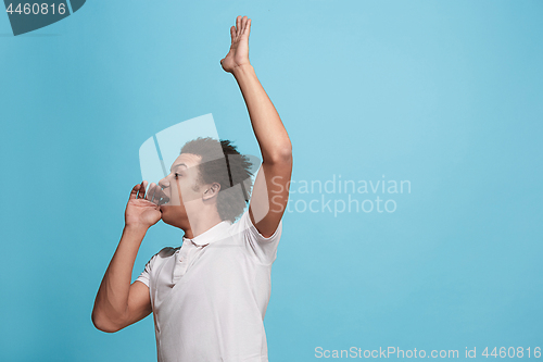 Image of Isolated on blue young casual man shouting at studio