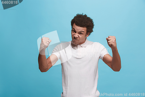 Image of The young emotional angry man screaming on blue studio background