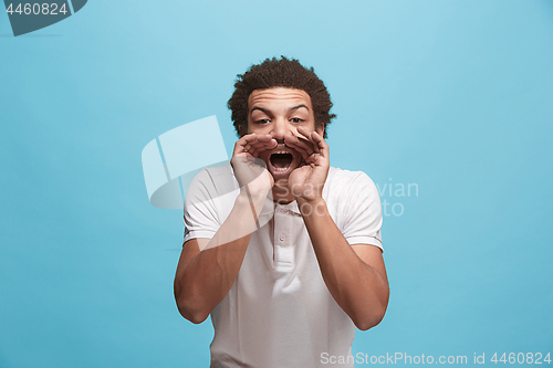 Image of Isolated on blue young casual man shouting at studio