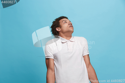 Image of Let me think. Doubtful pensive man with thoughtful expression making choice against blue background