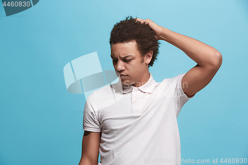 Image of Let me think. Doubtful pensive man with thoughtful expression making choice against blue background