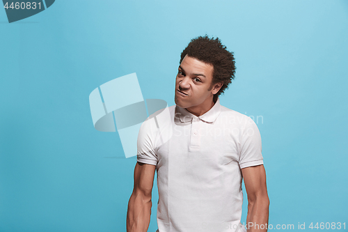 Image of The young emotional angry man screaming on blue studio background