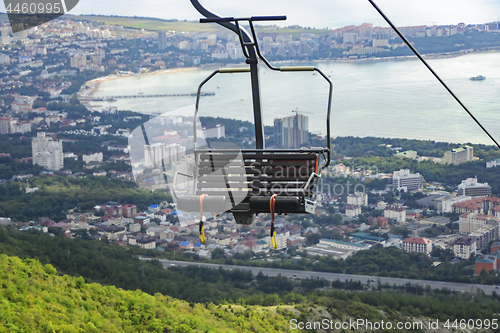 Image of Seats of cable car to mountains against backdrop of sea city below