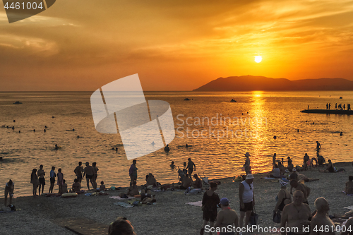 Image of Tourists enjoy nature and sunset on beach of sea