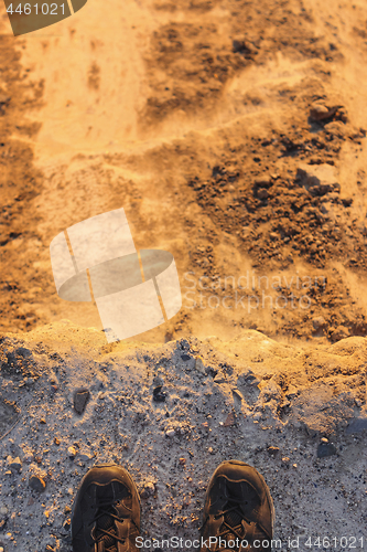 Image of Feet of man standing on edge of sandstone cliff