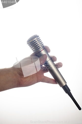 Image of Male hand holds microphone on white background