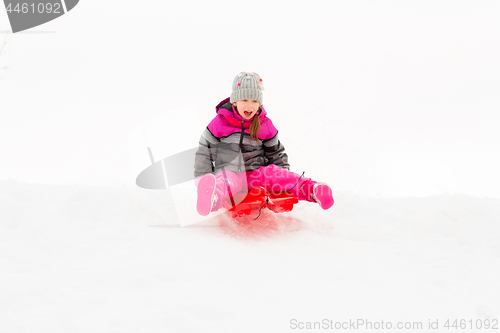 Image of happy little girl sliding down on sled in winter