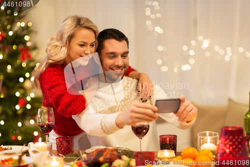 Image of happy couple taking selfie at christmas dinner