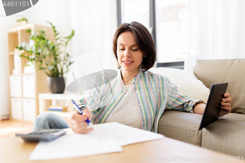 Image of woman with tablet pc, bills and calculator at home