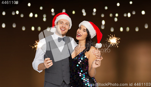 Image of happy couple in santa hats at christmas party