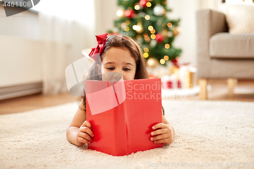 Image of happy girl reading book at home on christmas