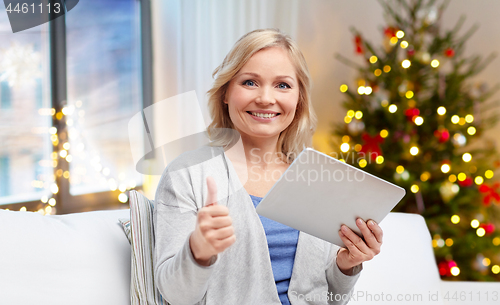 Image of happy woman with tablet pc at home on christmas
