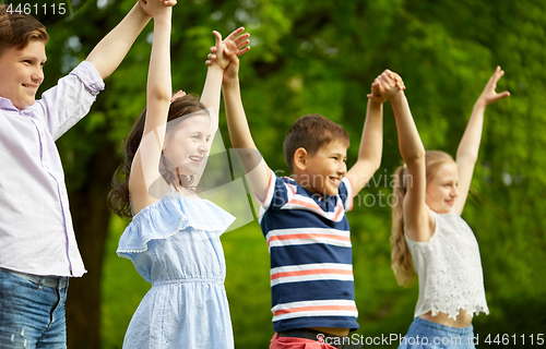 Image of happy kids holding raised hands in summer park