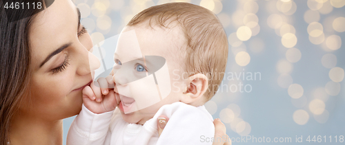 Image of mother with baby over festive lights background