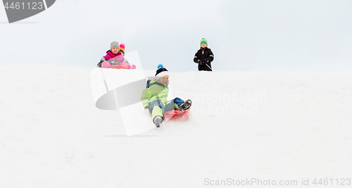 Image of kids sliding on sleds down snow hill in winter