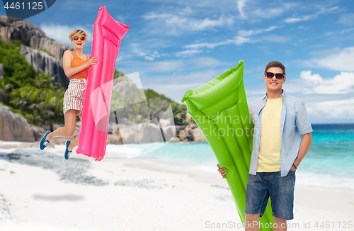 Image of teenage girl jumping with float mattress on beach