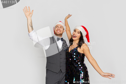 Image of happy couple in santa hats at christmas party