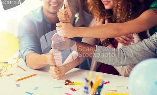 Image of team making thumbs up hand sign at office party