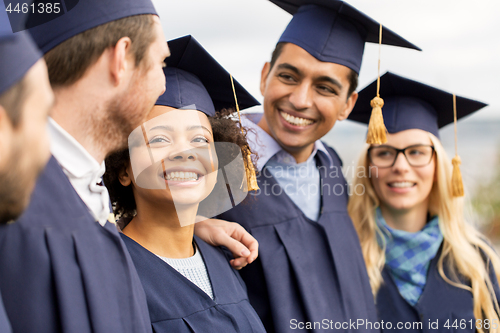 Image of happy students or bachelors in mortar boards