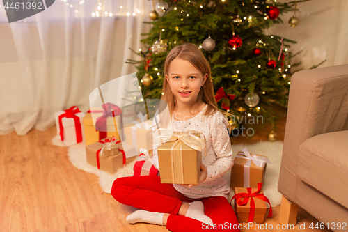 Image of smiling girl with christmas gift at home