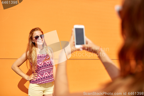 Image of teenage girl photographing friend by smartphone