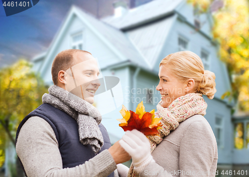 Image of smiling couple with autumn maple leaves over house