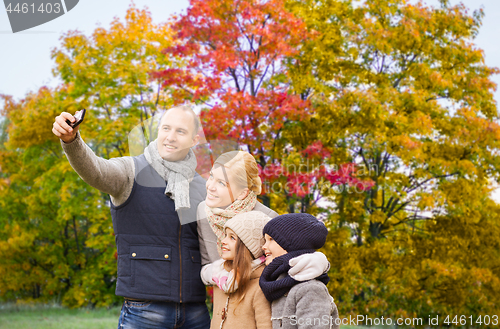 Image of family taking selfie by smartphone in autumn park