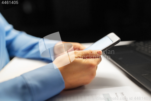 Image of close up of hands with smartphone at night office