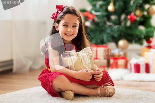 Image of happy girl with christmas gift at home