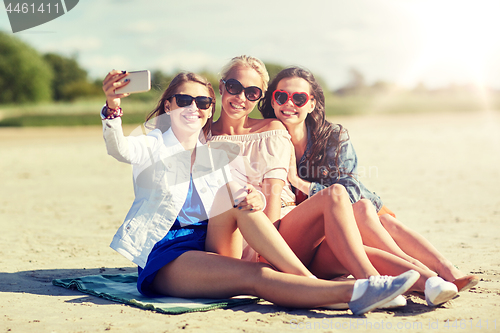 Image of group of smiling women taking selfie on beach