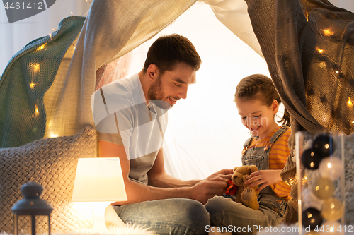 Image of happy family playing with toy in kids tent at home