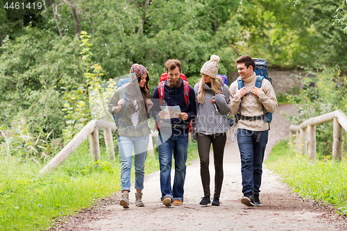 Image of friends or travelers hiking with backpacks and map